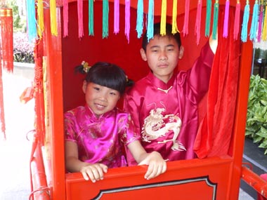 Two young children try out the bridal carriage before the bride dons her new red slippers and rides to the site of the wedding.